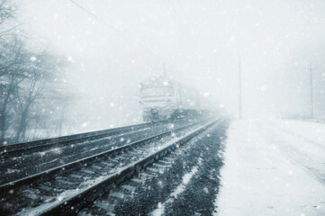 Railroad tracks vanishing into the perspective. Winter, Snow-covered railway. On railway tracks moving train. Duotone imge.