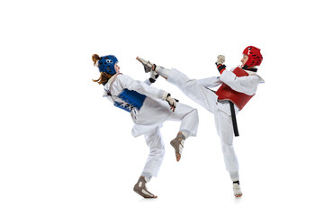 Portrait of two young women, taekwondo athletes practicing, fighting isolated over white...