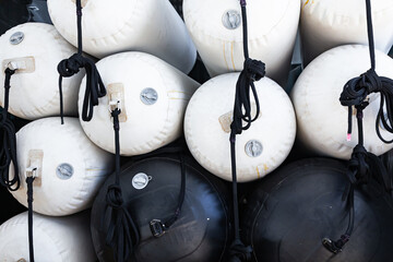 Inflatable fenders in black and white colors, to protect the hull of yachts during mooring, are...