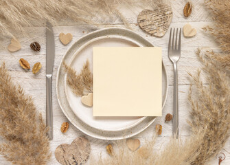 Wedding table place with blank card near dried plants and hearts top view, mockup