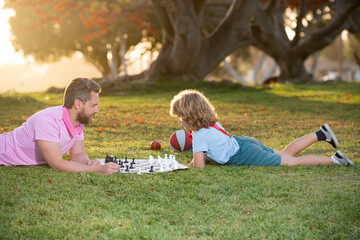 Father and son playing chess spending time together outdoor. Games and entertainment for children. Family concept.