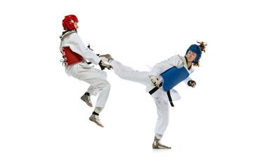 Fototapeta na wymiar Dynamic portrait of two young women, taekwondo practitioners training together isolated over white background. Concept of sport, skills