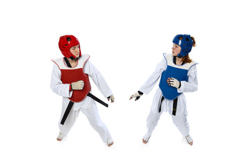Studio shot of of two young women, taekwondo athletes practicing together isolated over white background. Concept of sport, skills