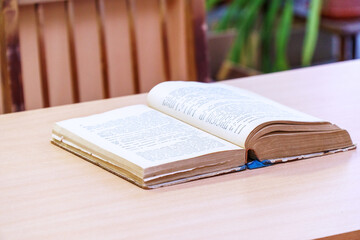 An open book on a wooden table. Selective focus
