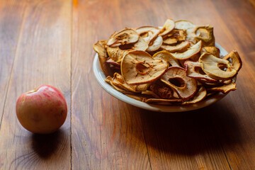 Ripe fresh healthy diet vegetarian food with vitamins. Dried apples in the form of rings on a plate on a wooden surface. Harvesting season.