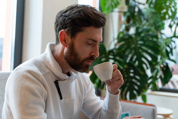 Portrait of attractive gentleman with closed eyes smelling fresh hot drink and smiling. Stock photo