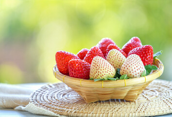 Fresh red and white strawberries in a wooden basket on blur background, Red Strawberry and Pine...