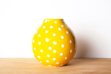 Bright yellow vase with white dots decorative on a white background