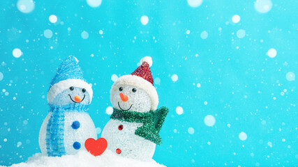 Winter snow snowman background holiday greeting card - Little cute Snowman and red heart on snow in snowy landscape with snowflakes blue sky and sunshine