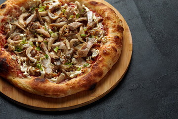 Appetizing pizza with mushrooms on dark background.