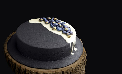 Black velour Velvet cake decorated with fresh blueberry and gold on wood tray