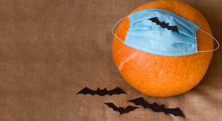Medical mask Pumpkin and decorative bats on canvas background, Halloween and autumn theme during coronavirus quarantine, place for text, selective focus	