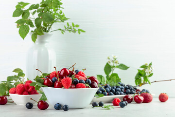 Various fresh berries on a white wooden table.