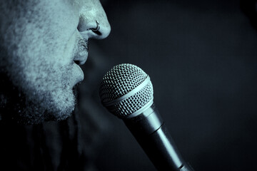 Singer man with round microphone on dark background