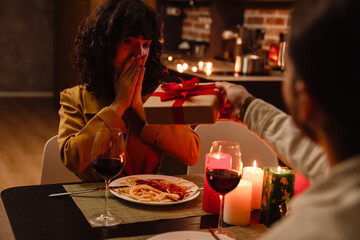 White man giving gift to his girlfriend during date in restaurant