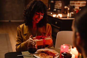 White man giving gift to his girlfriend during date in restaurant