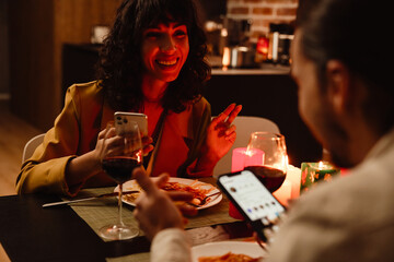 White couple talking and using cellphones during date in restaurant