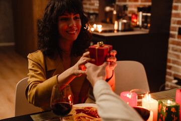 White man giving gift to his girlfriend during date in restaurant