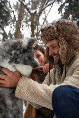 Married young couple on a walk in the winter forest with a pet dog husky