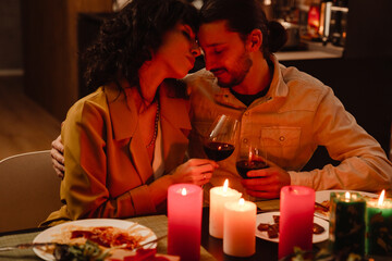 White couple hugging while having romantic dinner at home