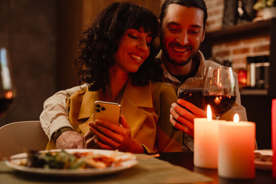 White couple using mobile phones during romantic date at home