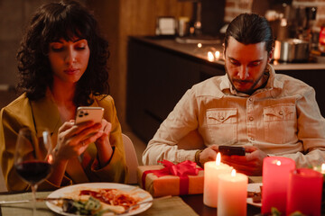 White couple using mobile phones during date in restaurant