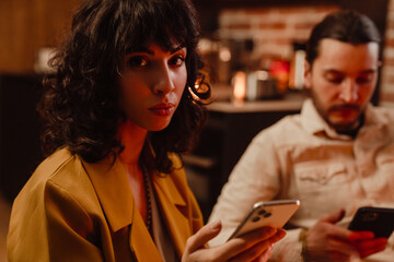 White couple using mobile phones during date in restaurant