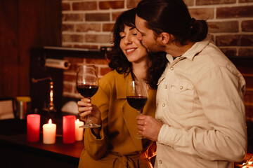 White romantic couple kissing while drinking wine at home