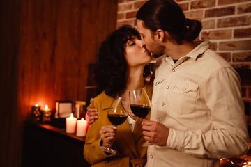 White romantic couple kissing while drinking wine at home