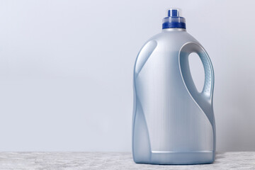 Gray large plastic bottle for liquid laundry detergent against the wall with copy space