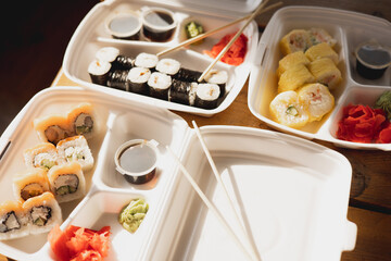Delivery sushi rolls in plastic food container. Japanese cuisine. Set of sushi rolls in disposable containers. Food delivery service and takeout concept