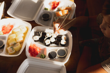 Obraz na płótnie Canvas Delivery sushi rolls in plastic food container. Japanese cuisine. Set of sushi rolls in disposable containers. Food delivery service and takeout concept