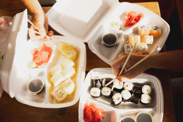 Delivery sushi rolls in plastic food container. Japanese cuisine. Set of sushi rolls in disposable...
