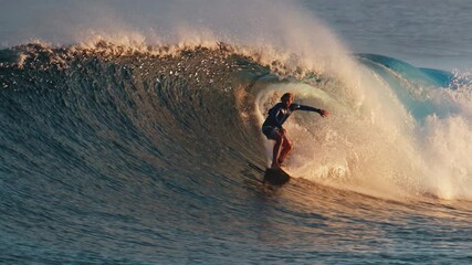 Surfer rides the powerful ocean wave at sunset