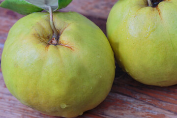  close-up, fresh quince with a leaf on a wooden board, top view