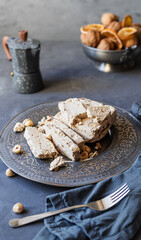 Halwa with hazelnuts, caffe pot, dry fruits, nuts, grey napkin, fork on grey background