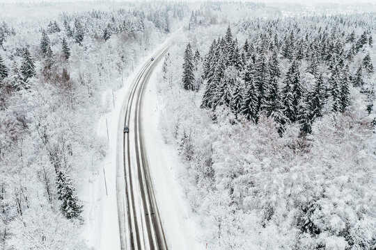Aerial view of winter road with cars in snow covered forest
