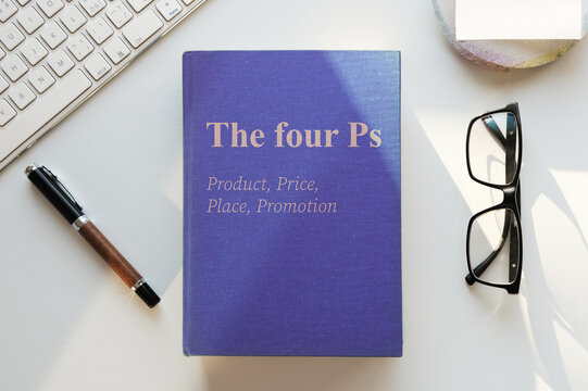 The four Ps marketing book illustration. Office desk table lit by evening sun. Top view, flat lay.