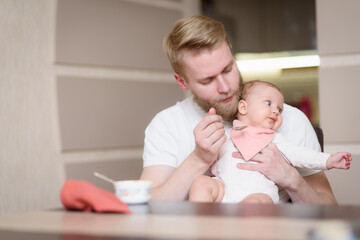 Father feeds his naughty little daughter who refuses to eat complementary foods