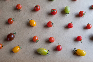 Multicolored cherry tomatoes are scattered on the table, upper view. Still life of cherry tomatoes for publication, poster, screensaver, wallpaper, postcard, banner, cover, post. Healthy diet