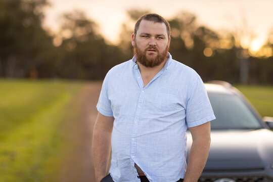 bearded man standing near car in the country