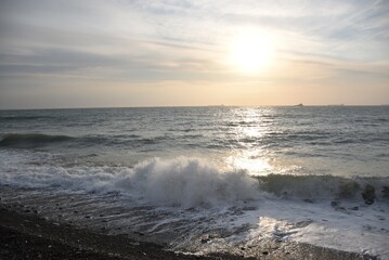 The last rays of the setting sun against the background of the calm running of the sea waves.