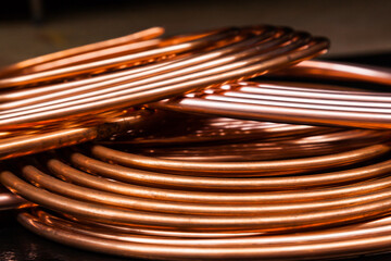 Twisted new copper tubes on a black background.
