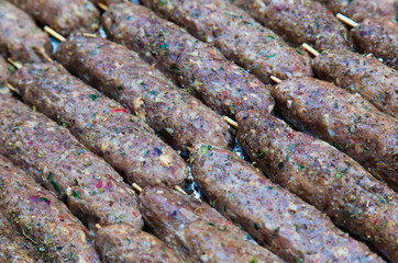 Raw minced meat on wooden sticks ready for grilling.