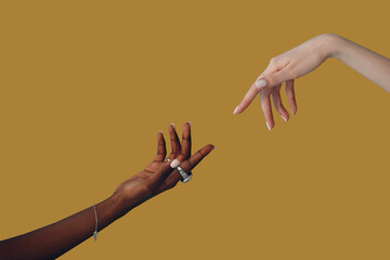Caucasian white and African American black hand reaching out to each other on brown background....