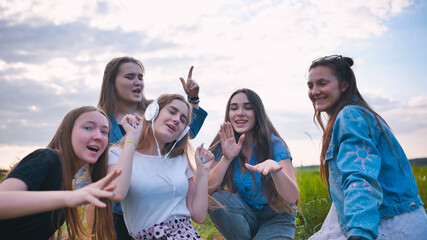 A group of girls of friends are listening to music on headphones and dancing to a friend.
