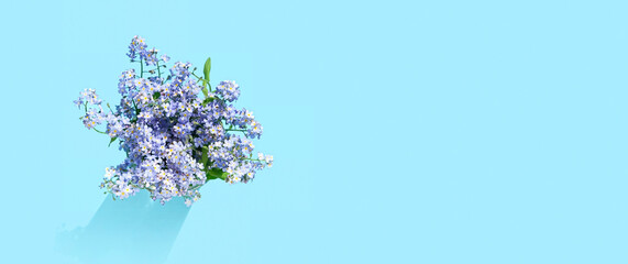 forget-me-not flowers bouquet on abstract blue background. small blue flowers close up. summer or spring season. romantic lovely nature image. banner. copy space. top view
