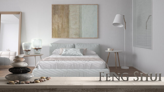 Wooden vintage table shelf with pebble balance and 3d letters making the word feng shui over blurred modern pastel bedroom with soft double bed, zen concept interior design