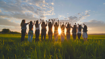 Silhouette of friends of 11 girls waving their hands at sunset in the field.