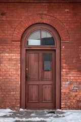 Fototapeta na wymiar Vertical shot of a vintage wooden door on an aged building with bricks and windows
